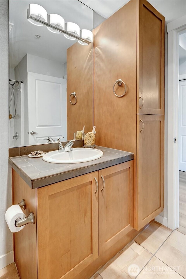 bathroom featuring baseboards, tile patterned flooring, and vanity
