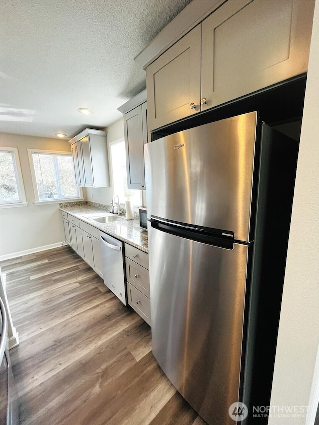 19573 2nd Ave NE, Poulsbo, WA 98366 - kitchen with stainless steel appliances, a sink, wood finished floors, baseboards, and a textured ceiling