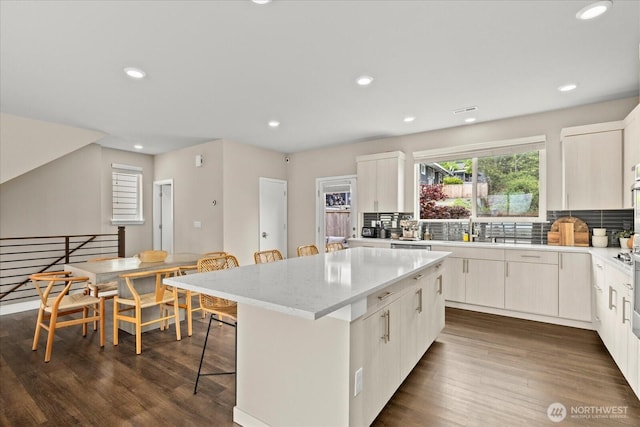 kitchen with recessed lighting, a kitchen breakfast bar, a kitchen island, and tasteful backsplash