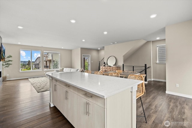 kitchen featuring baseboards, a kitchen island, dark wood-type flooring, and open floor plan