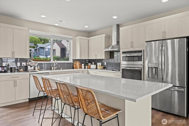 kitchen with a breakfast bar area, backsplash, wall chimney range hood, and stainless steel appliances