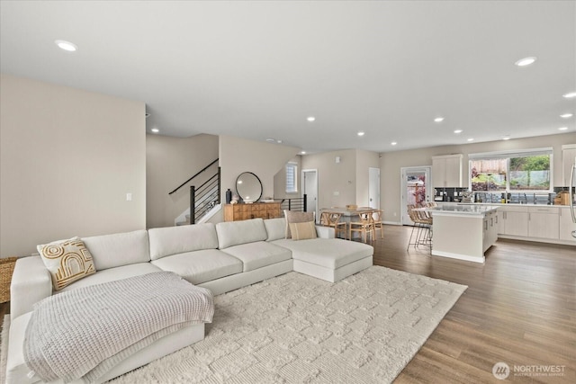 living room with stairs, recessed lighting, and wood finished floors