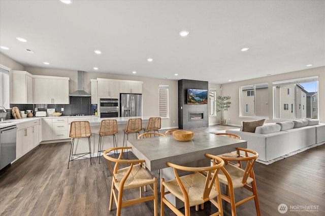dining room featuring baseboards, recessed lighting, a tile fireplace, and dark wood-type flooring