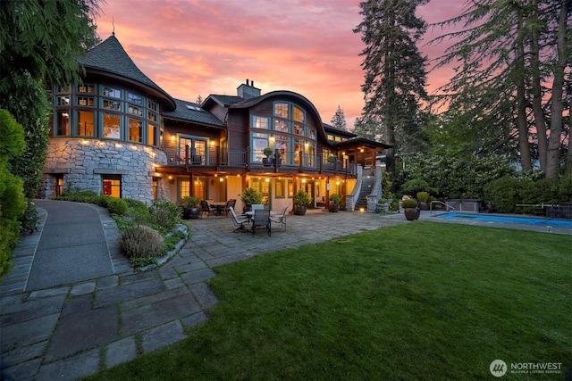 2141 Northshore Rd, Bellingham, WA 98226 - rear view of house with stone siding, a patio, a chimney, stairs, and a lawn