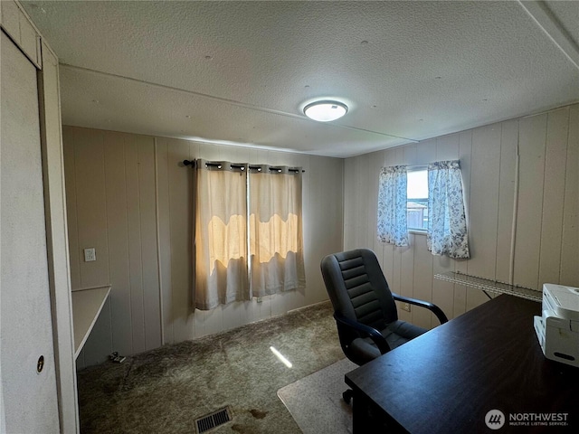 carpeted office featuring visible vents and wooden walls