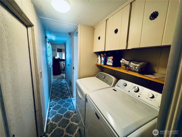 laundry area with separate washer and dryer, a textured ceiling, and cabinet space