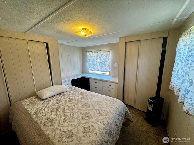 bedroom with wooden walls and dark colored carpet