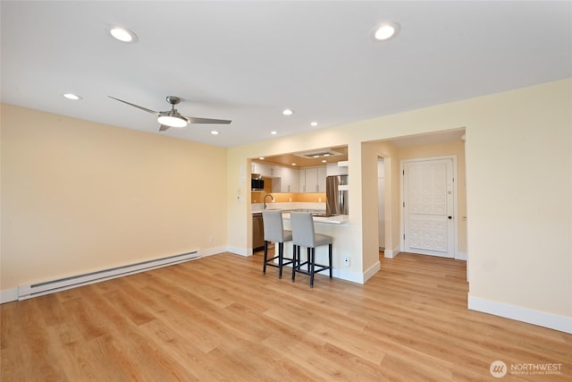 2320 43rd Ave E Unit 15A, Seattle, WA 98112 - kitchen featuring a baseboard radiator, appliances with stainless steel finishes, a kitchen breakfast bar, light countertops, and a ceiling fan