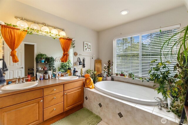 full bath featuring a sink, a garden tub, recessed lighting, and double vanity