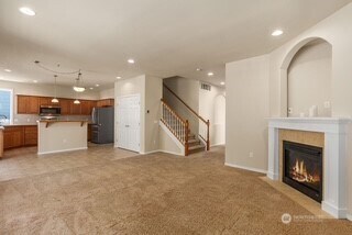 4504 5th Ave NW, Olympia, WA 98502 - unfurnished living room featuring recessed lighting, light carpet, a glass covered fireplace, and stairway