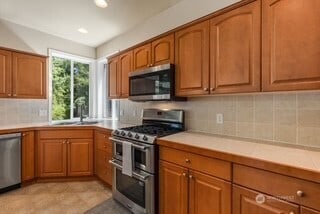 4504 5th Ave NW, Olympia, WA 98502 - kitchen featuring stainless steel appliances, brown cabinetry, light countertops, tasteful backsplash, and recessed lighting