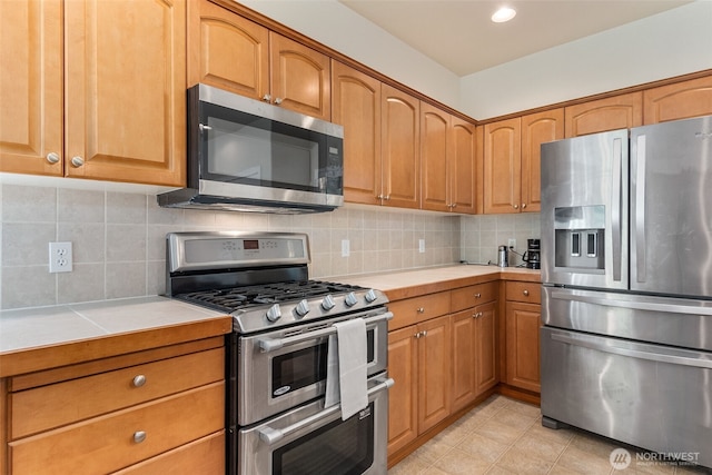 4504 5th Ave NW, Olympia, WA 98502 - kitchen with appliances with stainless steel finishes, tasteful backsplash, tile countertops, and brown cabinets