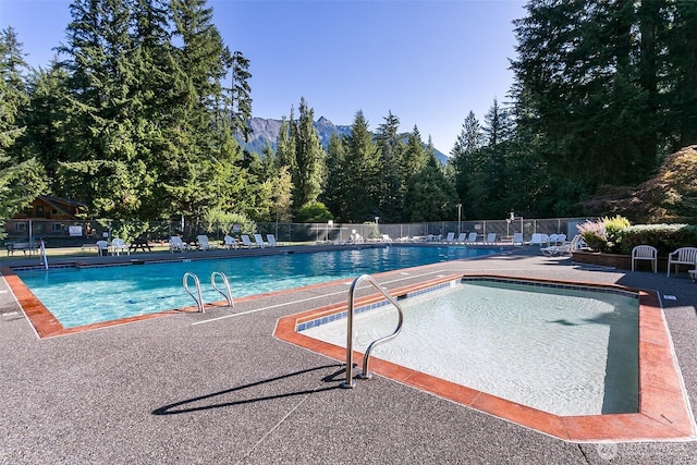 pool featuring fence, a mountain view, and a patio area