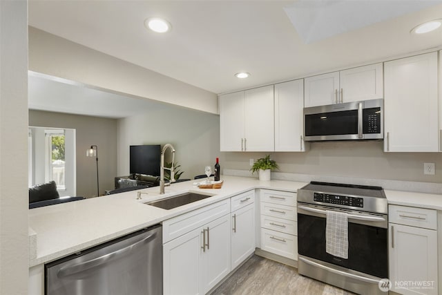 8957 Watson Pl NE, Bremerton, WA 98311 - kitchen featuring light wood finished floors, a sink, light countertops, white cabinets, and appliances with stainless steel finishes