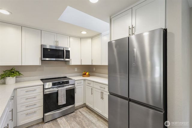 8957 Watson Pl NE, Bremerton, WA 98311 - kitchen featuring recessed lighting, light wood finished floors, white cabinetry, light countertops, and appliances with stainless steel finishes