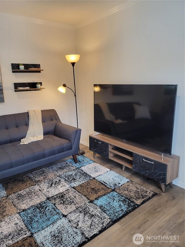 living area with baseboards, ornamental molding, and wood finished floors