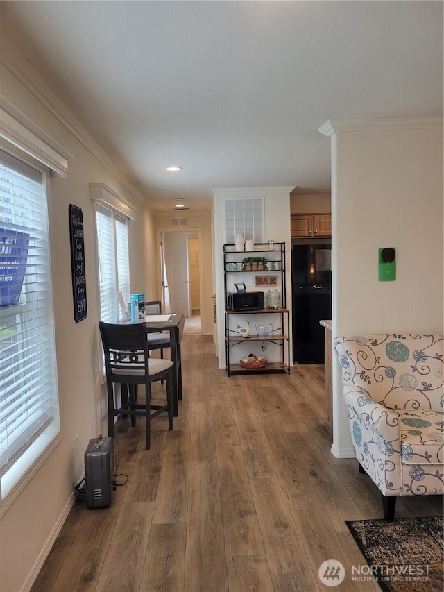 dining room with crown molding, baseboards, wood finished floors, and visible vents