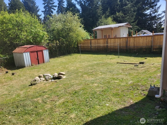 view of yard with a fenced backyard, an outbuilding, and a shed