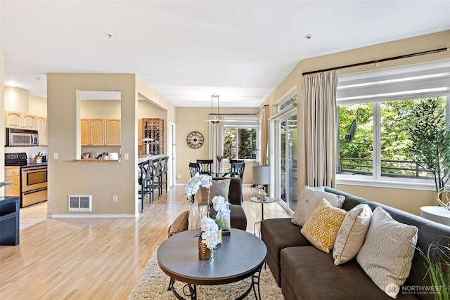 living room featuring baseboards, visible vents, and light wood finished floors