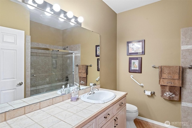 bathroom featuring vanity, baseboards, a tile shower, and toilet
