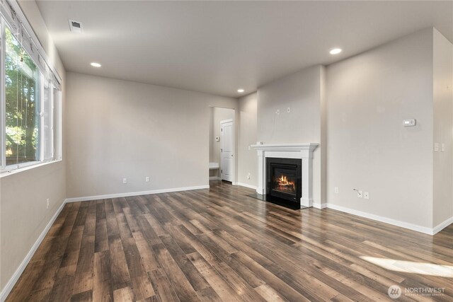 unfurnished living room with wood finished floors, recessed lighting, a fireplace with flush hearth, and baseboards