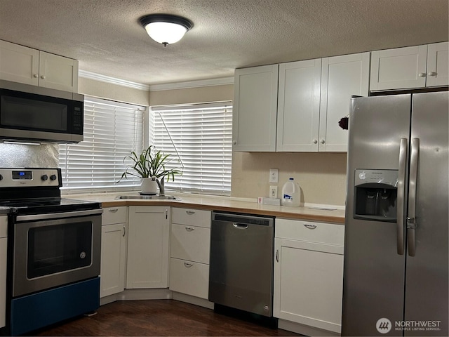 kitchen featuring white cabinets, appliances with stainless steel finishes, a sink, a textured ceiling, and dark wood finished floors