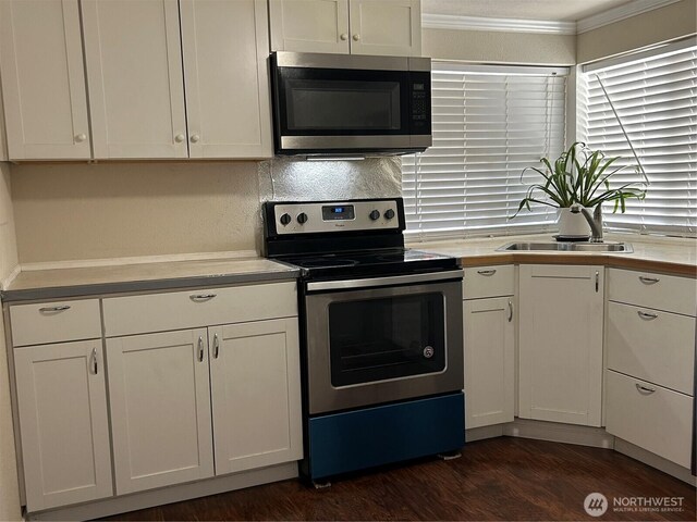 14118 37th Ave S, Tukwila, WA 98168 - kitchen featuring ornamental molding, dark wood-style floors, light countertops, white cabinets, and appliances with stainless steel finishes