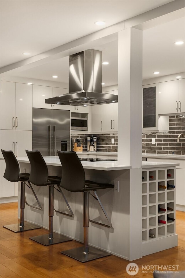 807 Lake St S Unit 300, Kirkland, WA 98033 - interior space featuring light wood finished floors, built in appliances, a kitchen breakfast bar, island exhaust hood, and backsplash