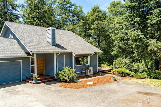 view of front of property featuring driveway, a chimney, roof with shingles, and a garage