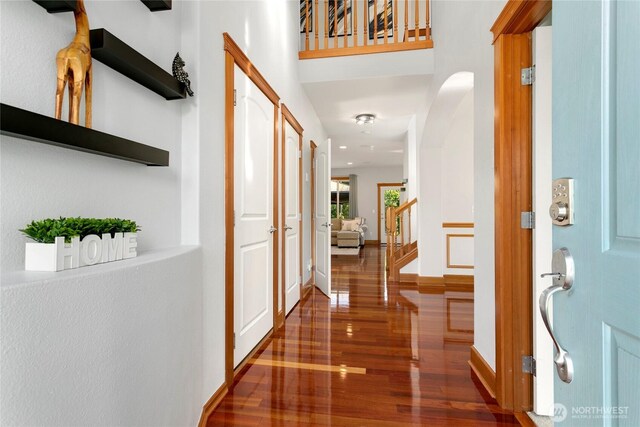hallway featuring wood finished floors, baseboards, and stairway