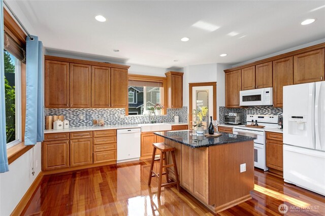 kitchen featuring white appliances, healthy amount of natural light, wood finished floors, and recessed lighting