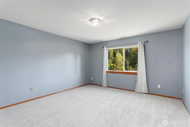 empty room featuring light colored carpet and baseboards