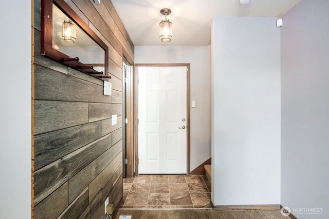 doorway to outside with baseboards and stone finish flooring