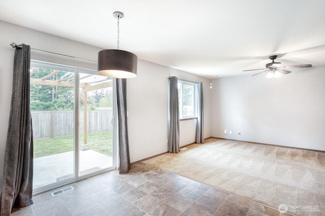 interior space with a ceiling fan, baseboards, visible vents, and stone finish floor