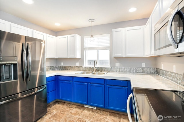 kitchen with light countertops, white cabinetry, blue cabinets, a sink, and appliances with stainless steel finishes