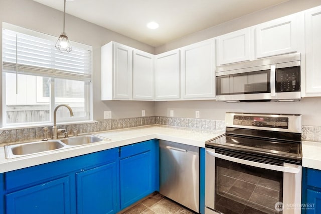 kitchen with a sink, appliances with stainless steel finishes, blue cabinetry, and light countertops