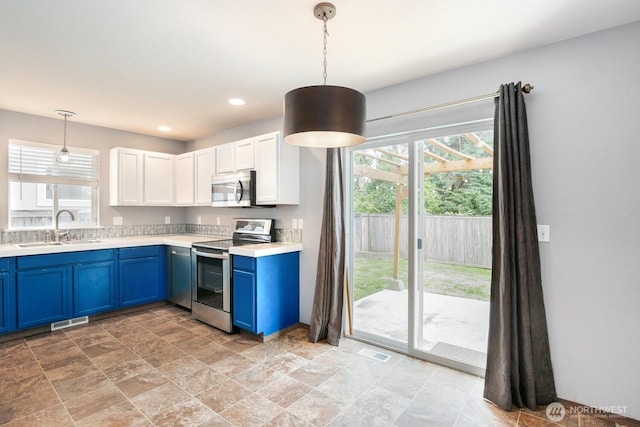 kitchen featuring visible vents, a sink, blue cabinetry, and stainless steel appliances