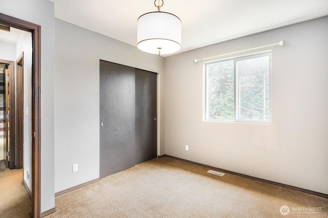 unfurnished bedroom with baseboards, carpet, and a closet