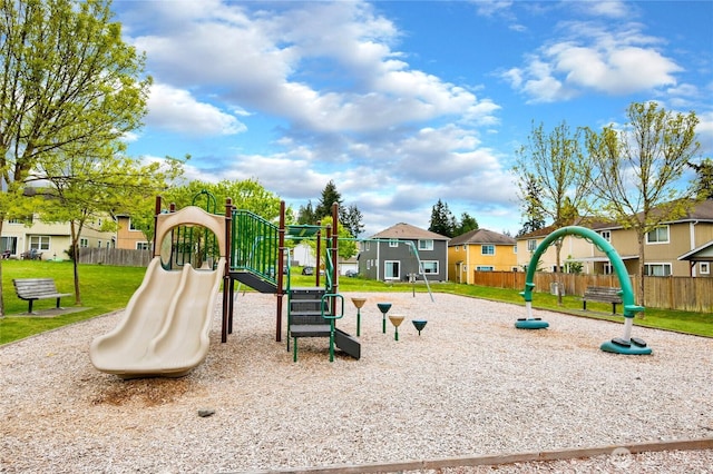 community play area featuring a lawn, fence, and a residential view