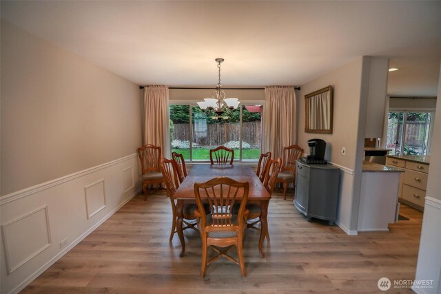 dining space with light wood finished floors, a chandelier, and a healthy amount of sunlight