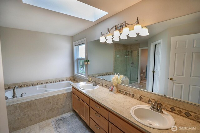full bath with a skylight, a sink, a garden tub, and a stall shower