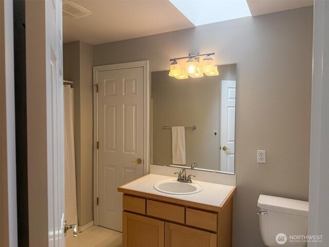 full bathroom featuring vanity, a skylight, and toilet