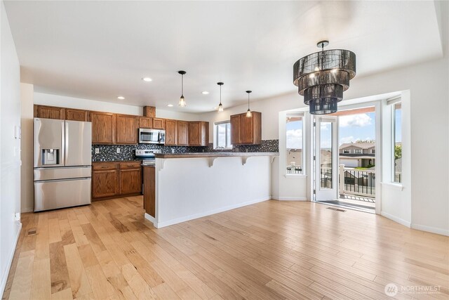 5208 Tumac Dr, Yakima, WA 98901 - kitchen featuring decorative backsplash, stainless steel appliances, brown cabinetry, and a peninsula