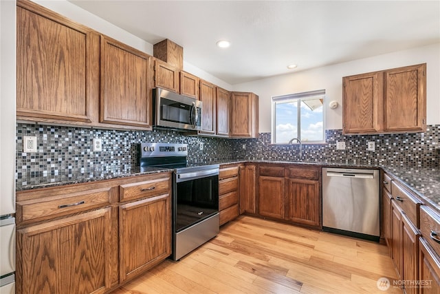 5208 Tumac Dr, Yakima, WA 98901 - kitchen featuring light wood-style floors, brown cabinets, a sink, dark stone countertops, and stainless steel appliances