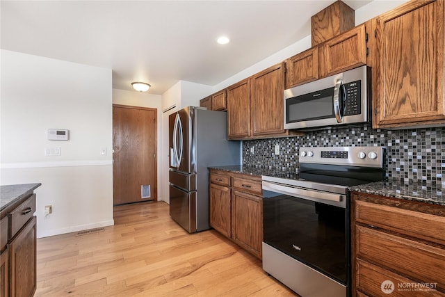 5208 Tumac Dr, Yakima, WA 98901 - kitchen with light wood-style floors, brown cabinetry, stainless steel appliances, tasteful backsplash, and visible vents
