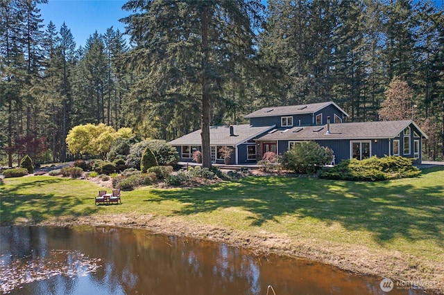rear view of property with a yard and a water view