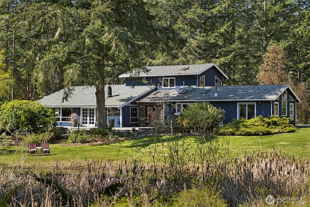 traditional home featuring a view of trees and a front lawn