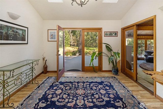 doorway to outside with baseboards, french doors, a notable chandelier, and wood finished floors