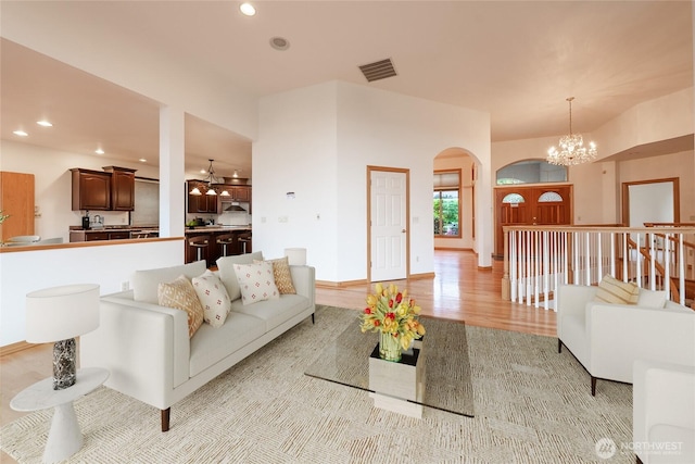6714 89th Street Ct E, Puyallup, WA 98371 - living room with arched walkways, a chandelier, recessed lighting, light wood-style floors, and baseboards