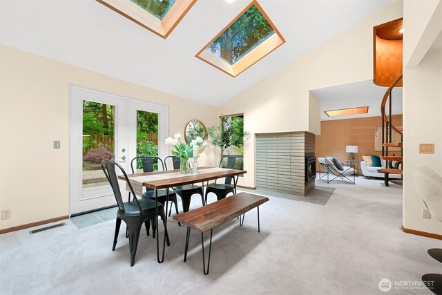 dining area with visible vents, carpet, a multi sided fireplace, and a skylight